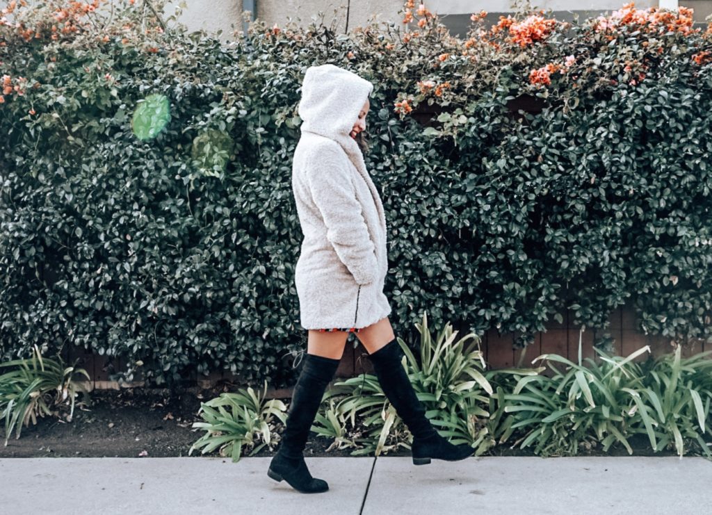 a woman walking in a beige teddy coat