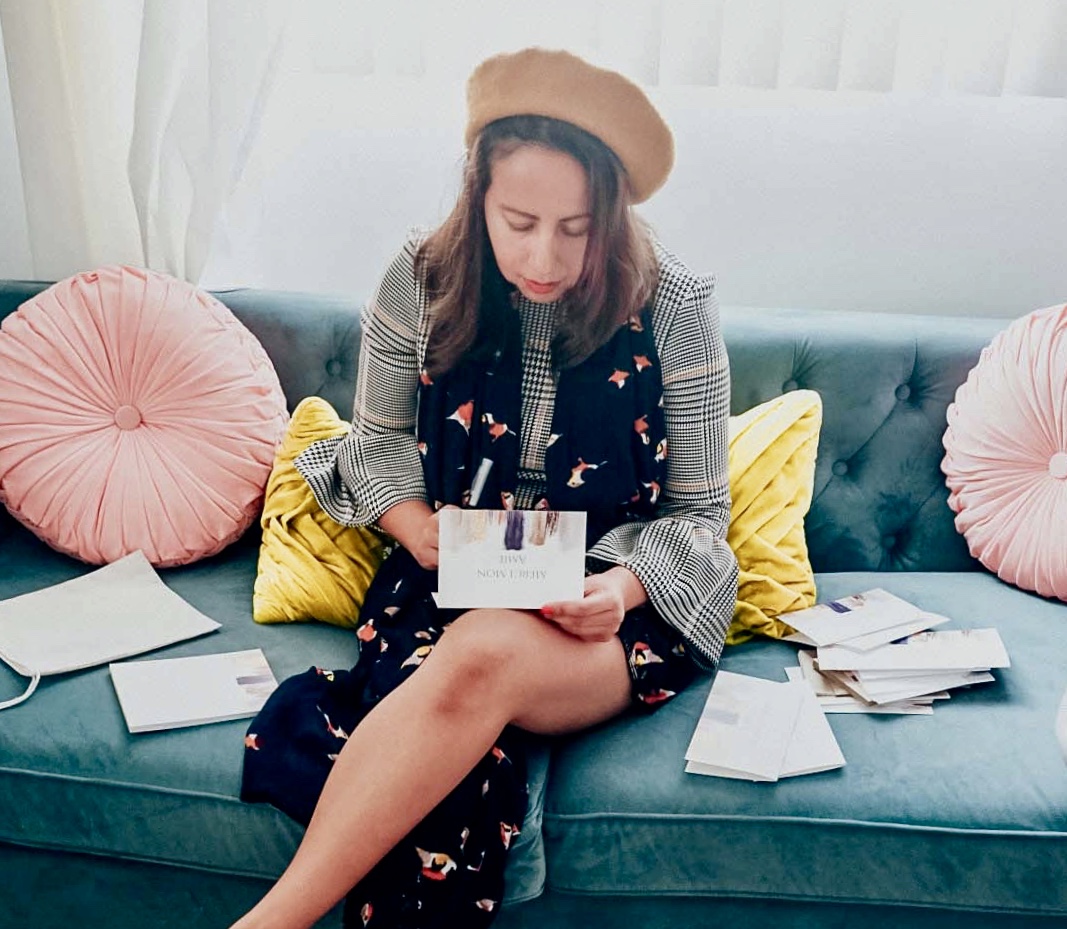 Girl in beret working on writing a note on customized stationer, which reads Merci Mon Amie. 