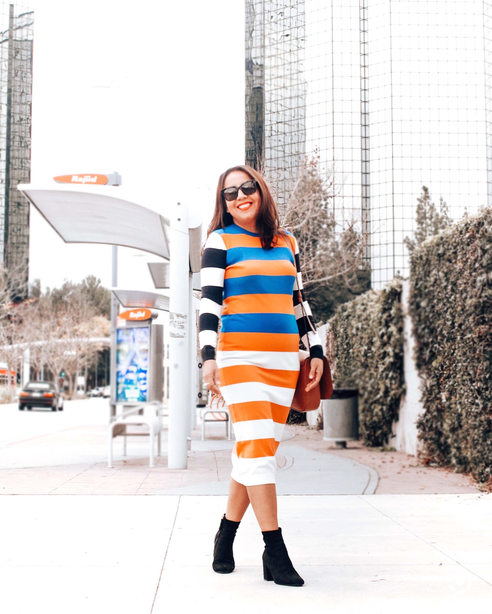 Girl in a striped sweater dress in the city. 