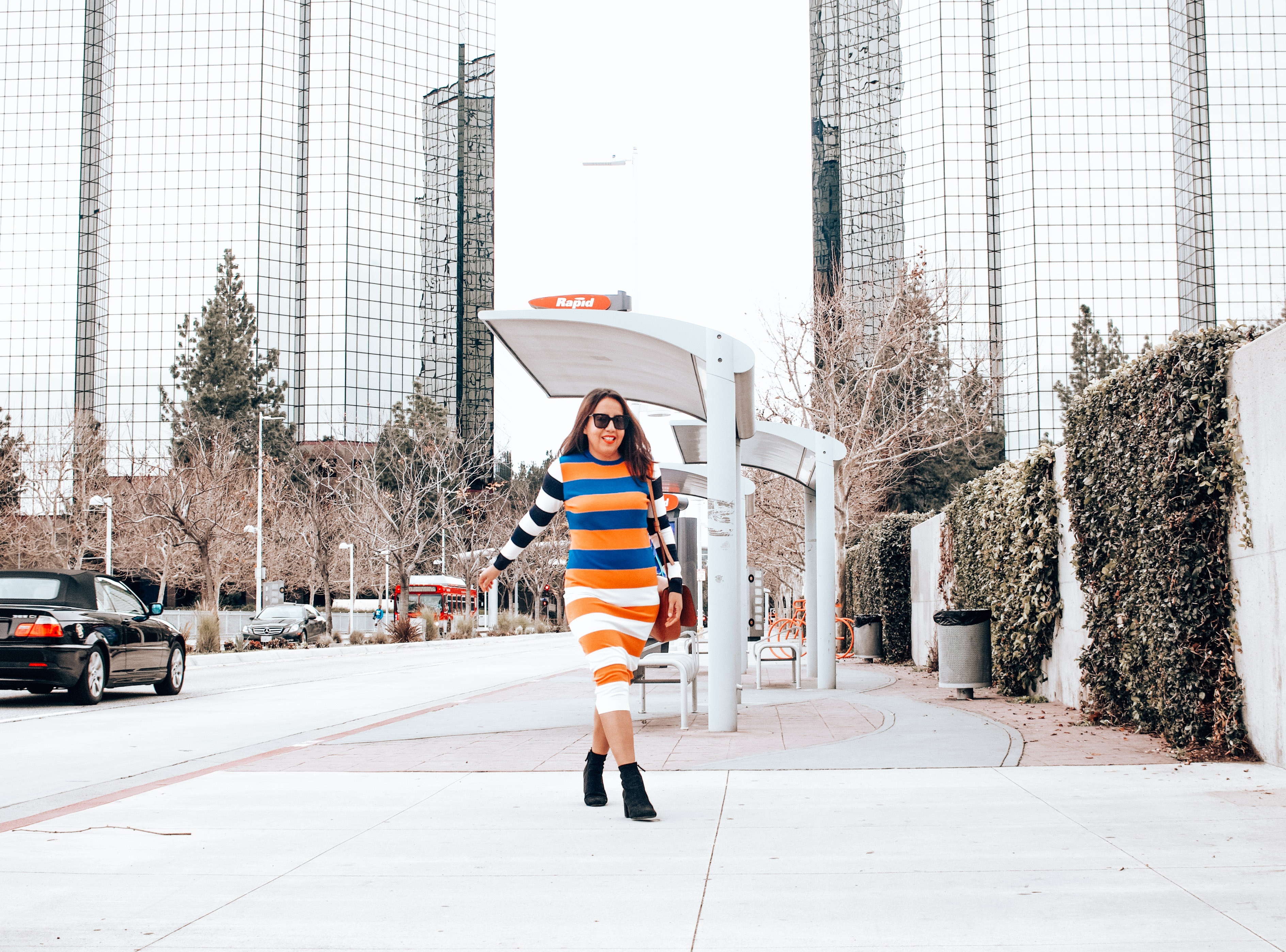 Girl in striped sweater dress walking in the city.