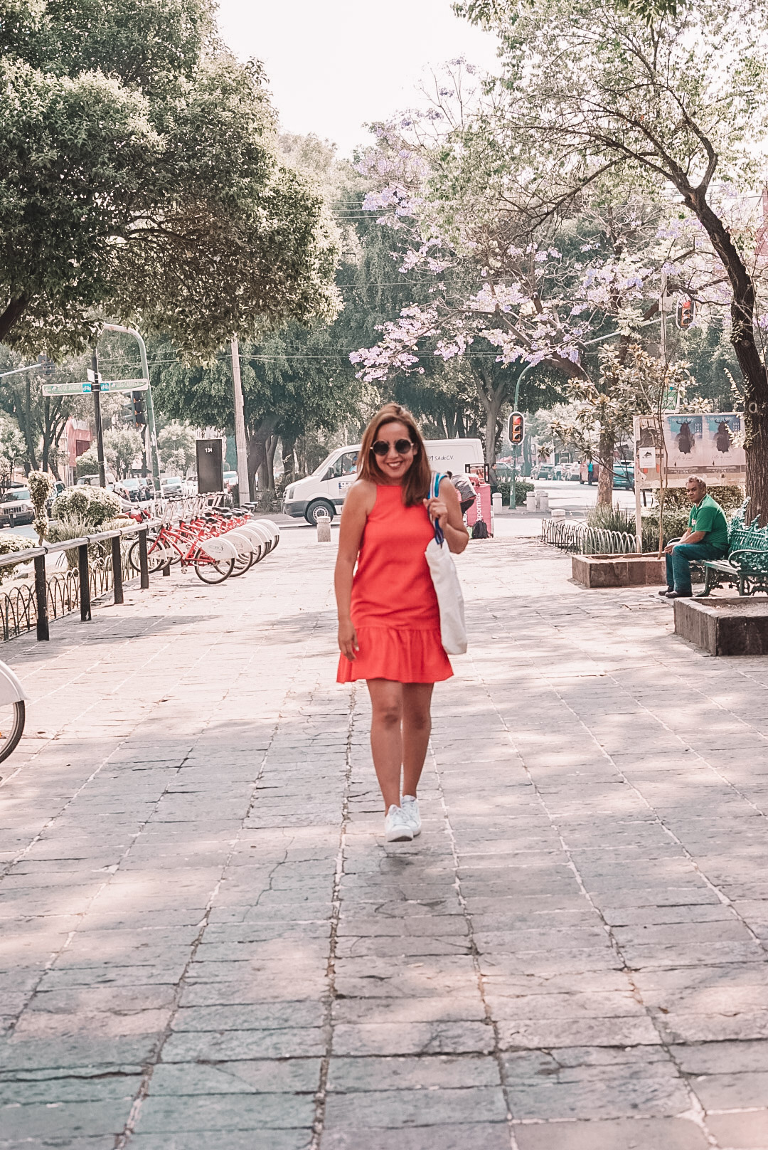 Woman in red dress walking in central avenue in Roma Norte. 