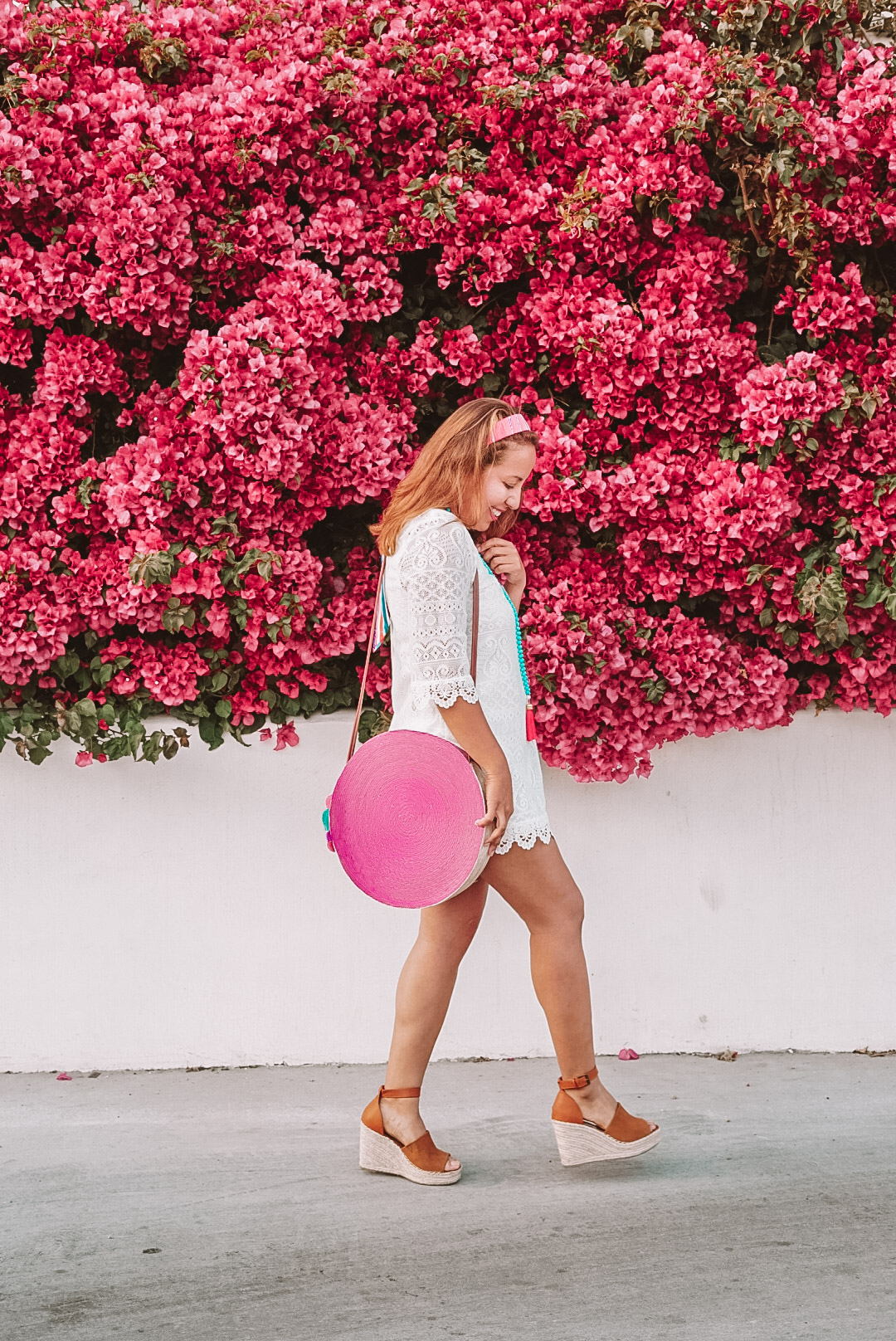 Girl in mini lace dress walking by flower wall in the Spring. 