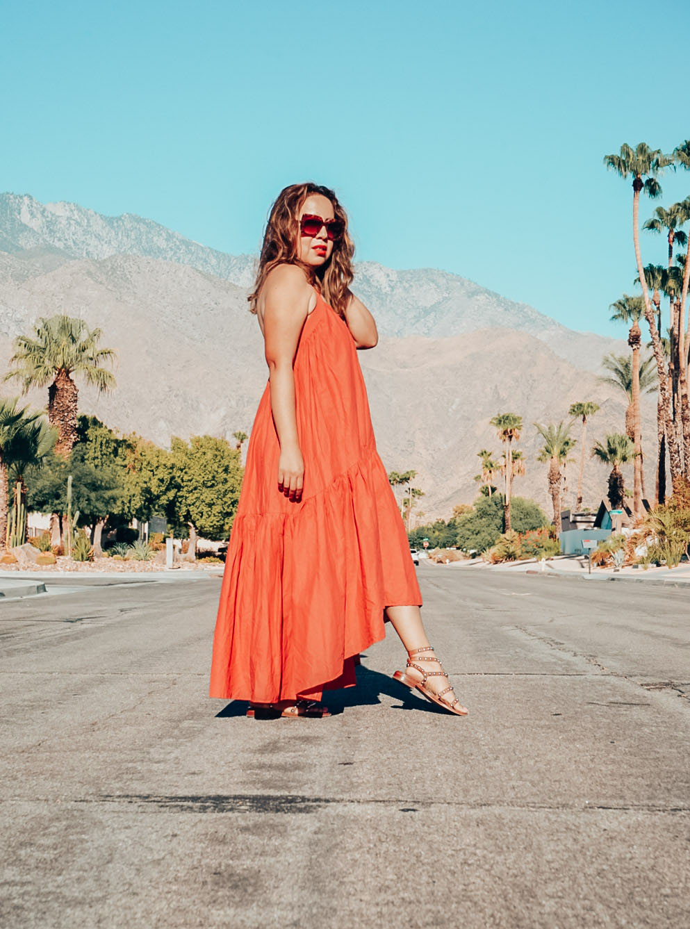 Girl standing in the dessert in an orange smock dress. 