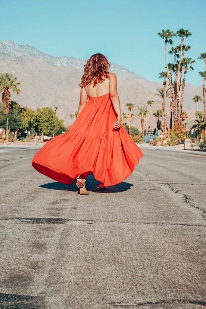 Girl in long orange dress walking in Palm Springs.